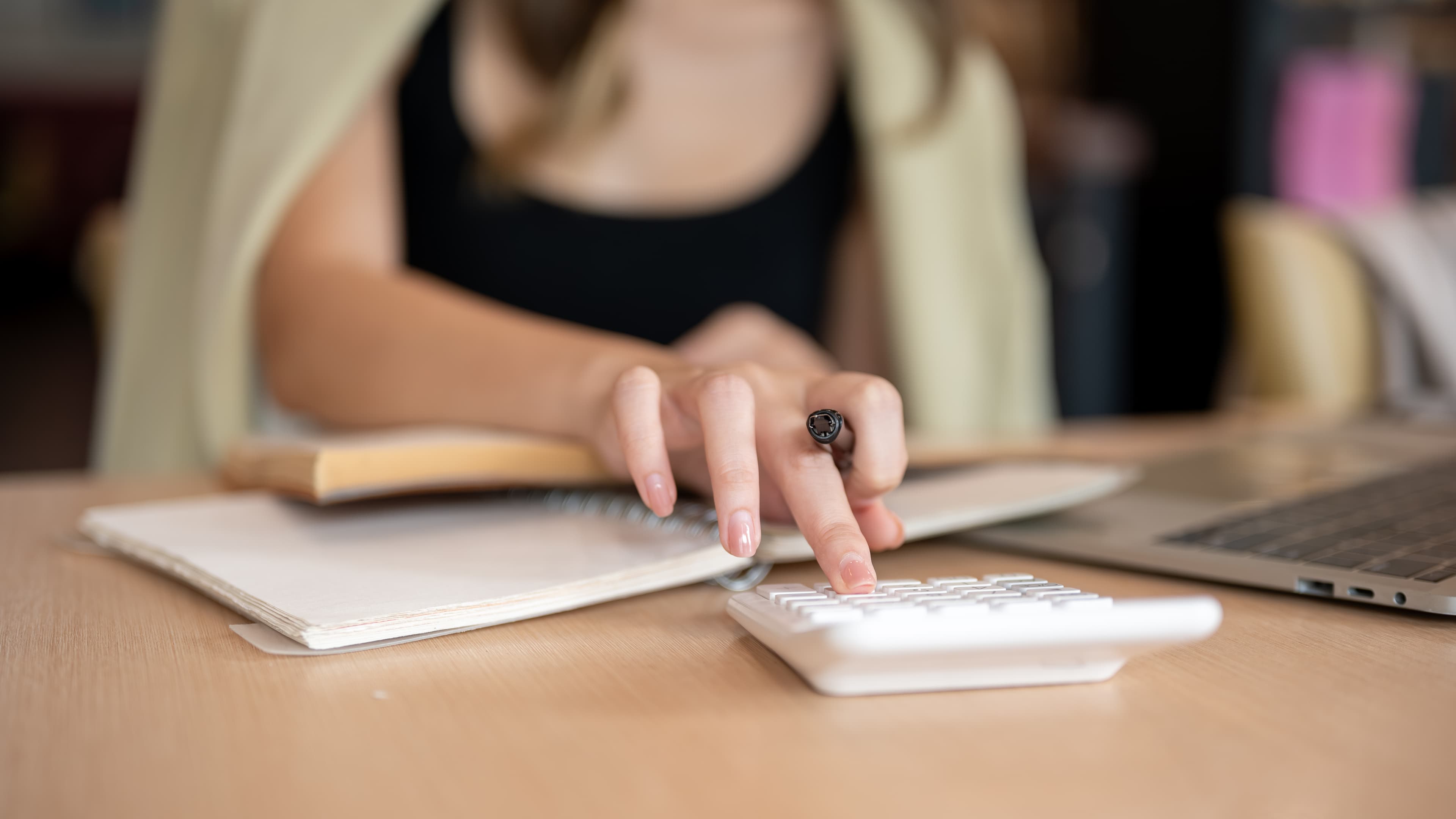 A hand holding a pen, reviewing and confirming line items.